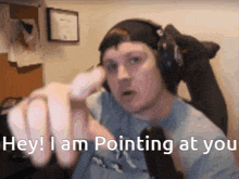 a man wearing headphones is pointing at the camera with the words " hey i am pointing at you " below him