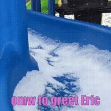 a blue slide covered in snow with the words `` omw to greet eric '' in pink letters .