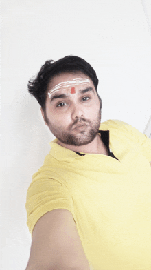 a man with a red dot on his forehead takes a selfie