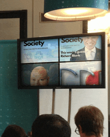 a group of people are sitting in front of a screen that says society on it