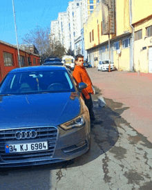 a man stands in front of an audi with a license plate that says 34 kj 6984