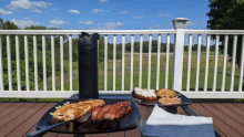 two plates of food on a deck with a bottle of water