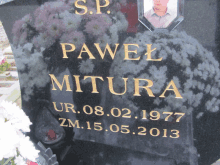 a gravestone for pawel mitura with flowers in the background