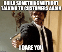 a man in a suit and tie is pointing a gun at someone and says `` build something without talking to customers again '' .