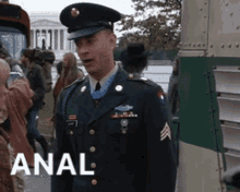 a man in a military uniform is standing in front of a bus with the word anal on the bottom