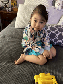 a little girl sits on a bed with a toy truck