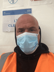 a man wearing a face mask stands in front of a sign that says nhs