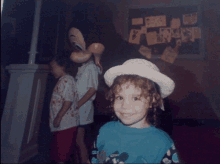 a little girl wearing a hat stands next to mickey mouse