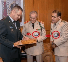 a man in a military uniform holds a piece of wood while two other men look on