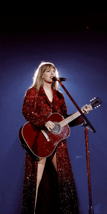 a woman in a red dress singing into a microphone while holding a red guitar