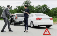 a man and a woman are talking to each other in front of a car .