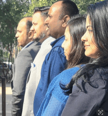 a group of people are standing in a line and one of them is wearing a blue shirt