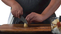 a person is cutting an apple on a wooden cutting board with a knife that says ' stainless steel ' on it