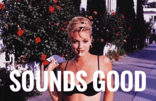 a woman in a bikini stands on a sidewalk with the words " sounds good " behind her