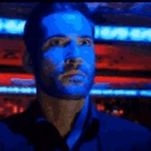 a man with a blue face is standing in a dark room .