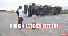 two men standing in front of a truck that is on its side with the words ouais c'est bien peté la