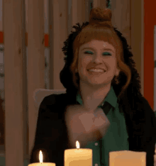 a woman in a green shirt is sitting at a table with candles .