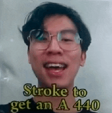 a man wearing glasses is smiling with the words `` stroke to get an a 440 '' written on his face .