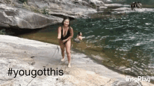 a woman in a bathing suit is standing on a rock near a body of water with the hashtag #yougotthis