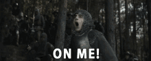 a man in a knight 's armor is screaming in the woods with the words " on me " above him