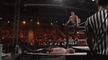 a wrestler is jumping over another wrestler in a ring that says gotham on the side