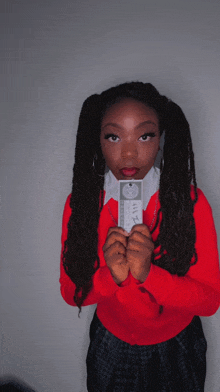 a woman in a red sweater is holding a piece of paper that says " ivy " on it