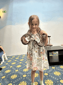 a little girl in a floral dress holding a snake