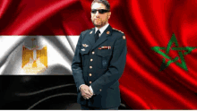 a man in a military uniform with sunglasses stands in front of a flag