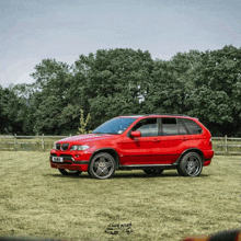 a red bmw is parked in a grassy field with trees in the background and a license plate that says eh83