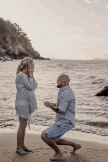 a man kneeling down to propose to a woman on a beach