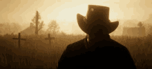 a man wearing a cowboy hat is standing in a cemetery .