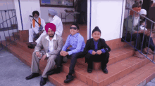 a man in a turban sits on a set of stairs next to two boys