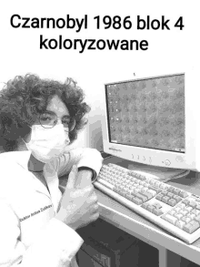 a black and white photo of a man wearing a mask and giving a thumbs up in front of a computer