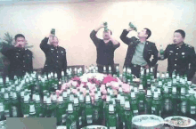 a group of men are standing around a table full of beer bottles .