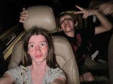 a boy and a girl in the back seat of a car making funny faces