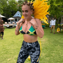 a woman in a bikini and tie dye pants stands in a field