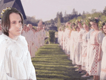 a man in a white shirt stands in front of a row of women with flower crowns on their heads