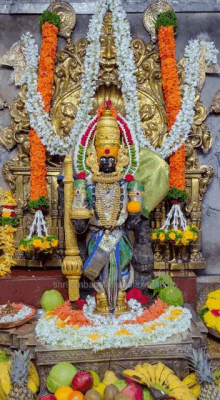 a statue of a deity is surrounded by flowers and fruit