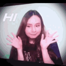 a woman is waving her hands in front of a screen with the word hi written on it .