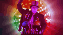 a man wearing a top hat and glasses is standing in front of a disco ball