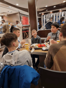 a group of young boys are sitting at a table in a mcdonald 's