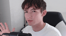 a young man in a white shirt is sitting in front of a black and white chair