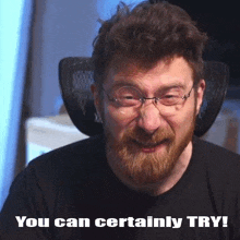 a man with a beard and glasses is sitting in a chair and making a face .