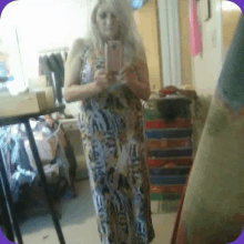 a woman in a dress is taking a picture of herself in the mirror