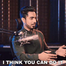 a man sitting in front of a microphone with the words " i think you can do it " below him