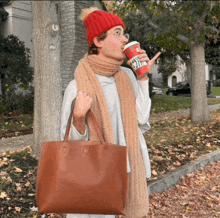 a woman wearing a red hat and scarf is holding a starbucks cup