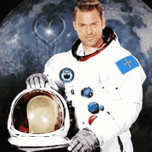 a man in a space suit holds a helmet in front of a moon