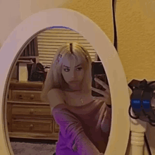 a woman is taking a selfie in front of a mirror .