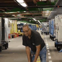 a man in a black shirt is kneeling down in a warehouse with a sign that says " no smoking "