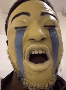 a man with yellow paint on his face and blue tears running down his face